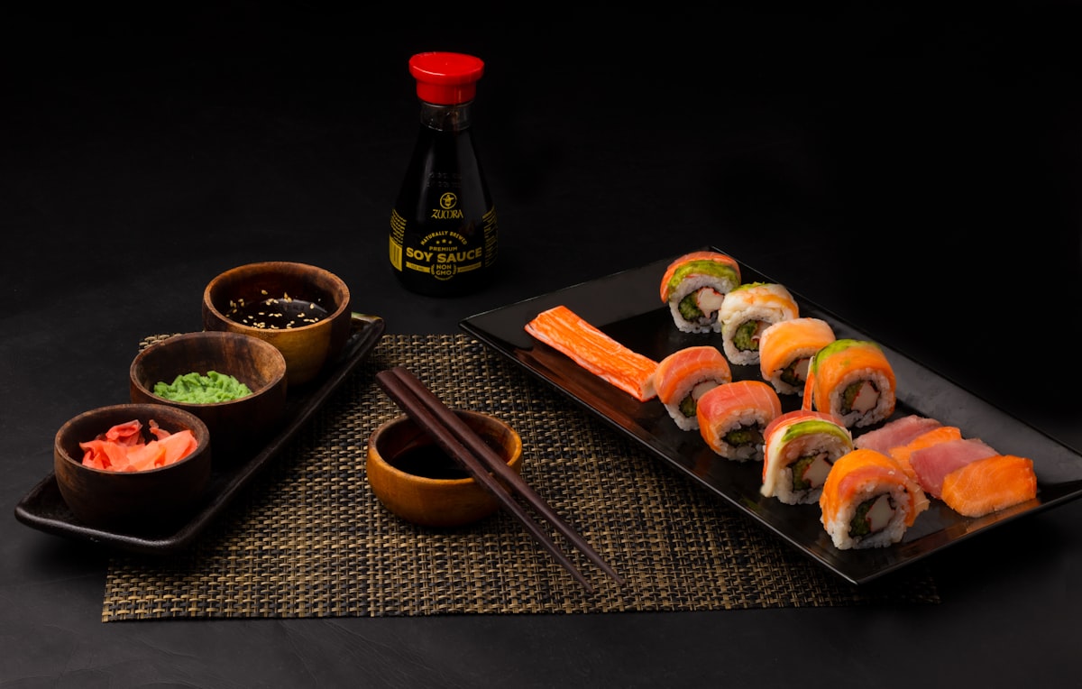 Sushi on black ceramic plate beside sauce bottle